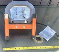 Front view showing lamp housing, stand, bulb, tape measure for scale