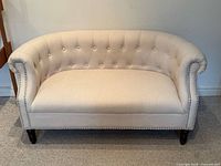 Front view of beige tufted settee showing overall condition and design