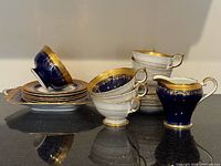 Group view of cups, saucers, plates and cream jug showing pattern and gilding