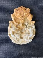 Front view of carved jade pendant showing dragon and phoenix motif