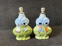 Front view of both porcelain sprinkler perfume bottles showing painted Dutch children scene