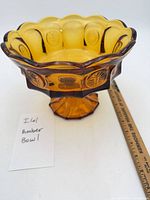 Full view of amber pedestal bowl beside ruler and note