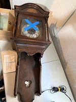 Full view of wooden wall grandfather clock case, upper door taped, lower case open