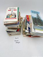Two stacks of assorted folding road maps