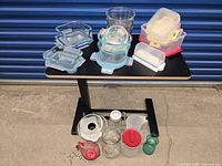 Overall view of containers on table, showing glass and plastic storage pieces and pitchers