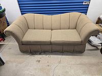 front view of beige sofa showing rolled arms, pleated skirt, two seat cushions