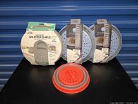 All four microwave splatter shields—three large in packaging, one small red/gray cover