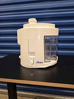 Front side view of Oster Model 3165 juicer showing motor base and attached containers