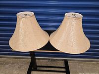 Front view of both beige bell lampshades on table