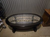 full view of oval coffee table showing glass top and iron scrollwork