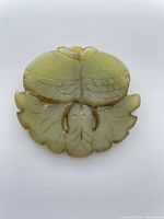 Front view of carved green stone double-fish pendant