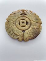 Front view of carved stone pendant showing motifs