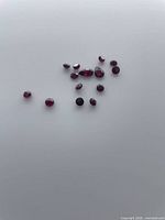 Group of loose garnets spread on surface showing quantity, shapes and colour