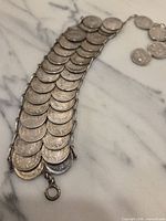 Full view of coin bracelet showing overlapping coin arrangement and clasp