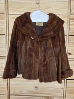 Full view of brown fur jacket on hanger