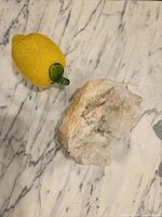 Quartz geode half next to lemon for scale on marble surface