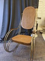 Full front angle of rocking chair showing metal frame and cane panels