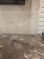 Front view of clear lucite magazine holder showing handle and legs