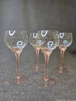 four clear bowl glasses with pink spiral stems