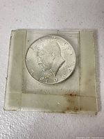 Obverse of 1964 Kennedy half dollar in plastic flip