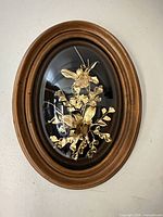 Front view showing entire oval framed gilded orchid arrangement