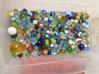 overview of entire group of mixed glass marbles in storage bin
