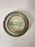 Top view of clear smoky glass ashtray showing printed Palm Springs Spa Hotel logo