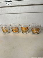 Front view of the four gold gilded souvenir rocks glasses