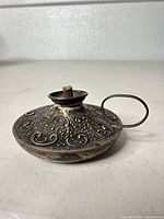 Top angled view of sterling chamberstick showing ornate repousse and ring handle