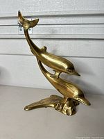 Front view of brass double-dolphin sculpture on base