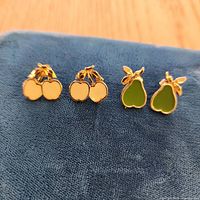 Front view of both cherry and pear stud earring pairs on fabric pad