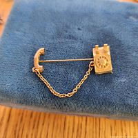 Full view of brooch with handset, chain and phone base