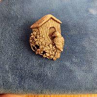 Front view of brooch showing birdhouse, bird, and floral details