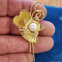 Front view of gold-tone floral brooch with simulated pearl center