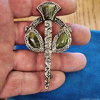 Front view of brooch held in hand showing overall design and stones