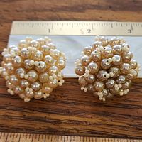 Front view of both champagne faux pearl cluster earrings beside ruler