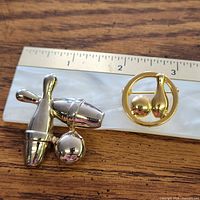 Front view of both brooches beside ruler for scale