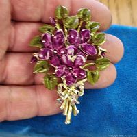 Front view of floral brooch in hand for scale