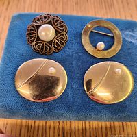 Four brooches on blue pad showing fronts