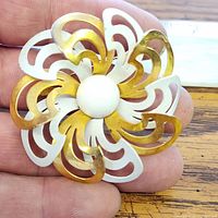Front view of layered gold-tone and white enamel floral brooch showing design and size reference