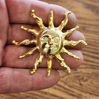 Front view of gold-tone sunburst brooch on wood surface