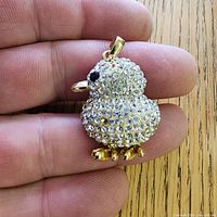 front view of gold tone rhinestone chick pendant in hand