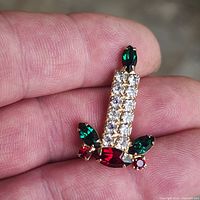 Front view of candle brooch showing clear, green and red rhinestones in gold-tone setting