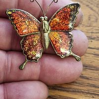 Front view of brooch showing multicolor glitter enamel wings and gold-tone body