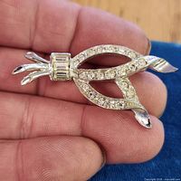 Front view of silver-tone ribbon brooch with clear rhinestones