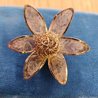 Front view of six-petal silver tone flower brooch showing mesh-texture petals and filigree center