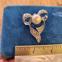 Front view with ruler showing size and detail of rhinestones and faux pearl