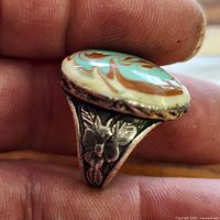 Side view of ring showing marbled cabochon and floral shoulder design