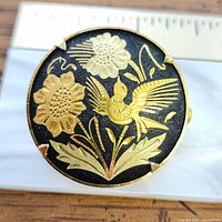 Front view showing bird and flower gold motif on black enamel