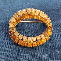 Front view of oval brooch showing yellow and clear rhinestones